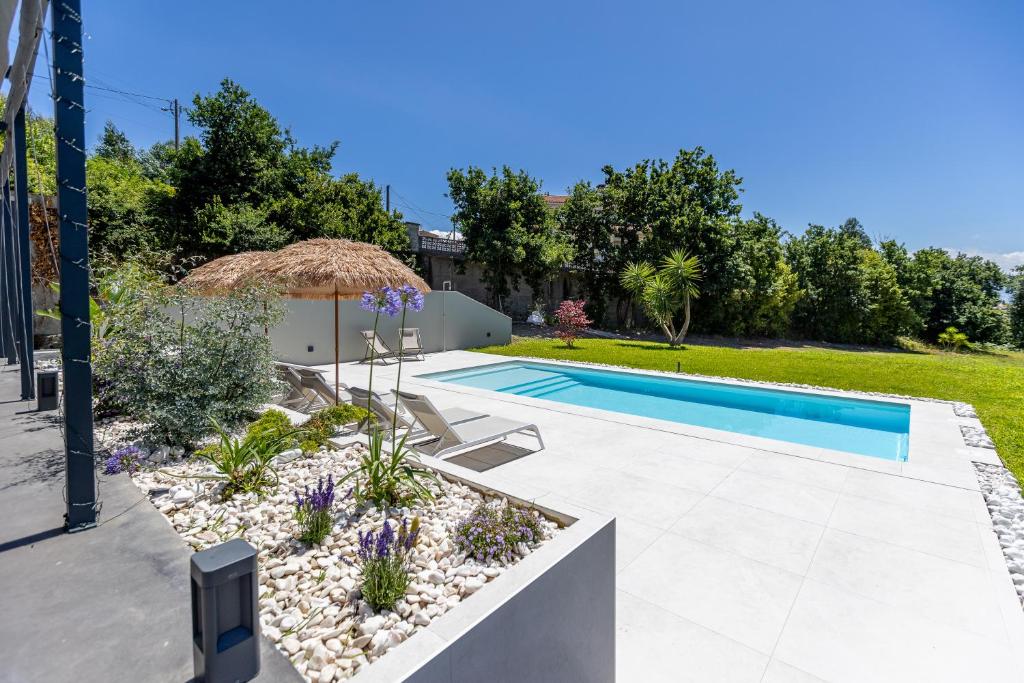 a swimming pool with an umbrella and a garden at Prado Essence in Sanxenxo