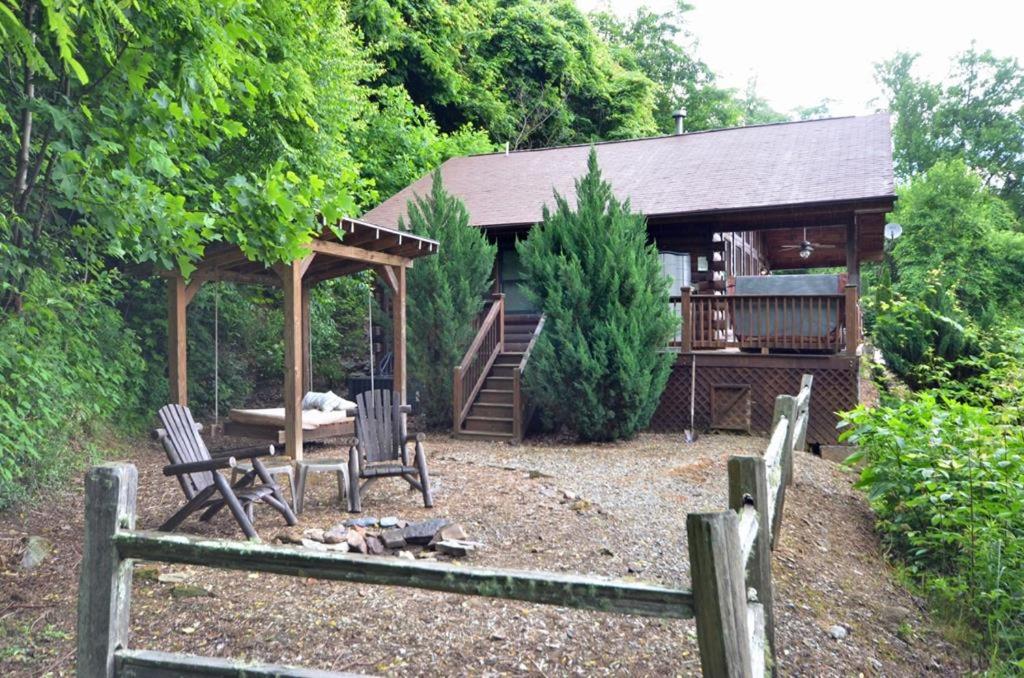 a cabin with two chairs and a table and a fence at Free Railroad Tix - secluded - Fire Pit and Outdoor Bed Swing in Talc Mountain