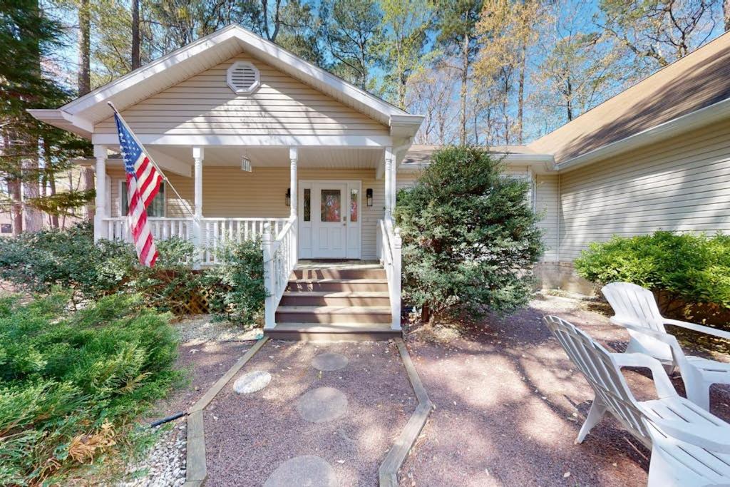 a house with a flag and two white chairs at Salty Way in Ocean Pines