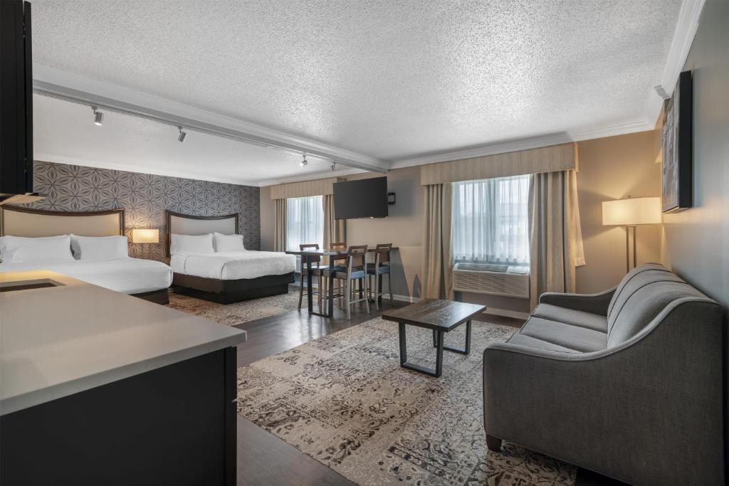 a hotel room with two beds and a living room at Best Western PLUS Franklin Square Inn in Troy