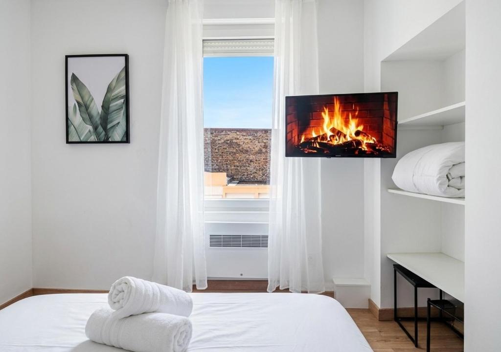 a white bedroom with a fireplace in a window at L'Opale in Roanne