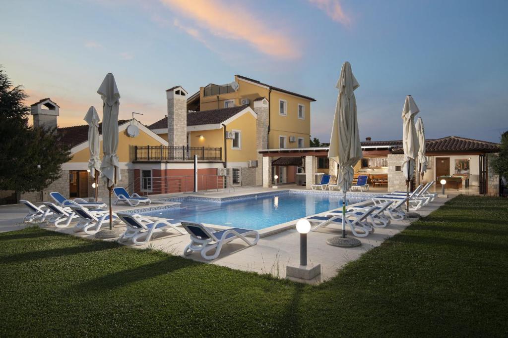 a pool with chairs and umbrellas in front of a house at Villa Suzanne in Banjole