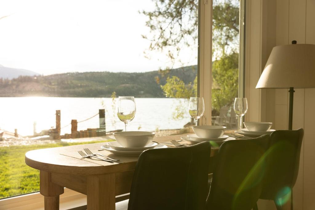 a wooden table with glasses and chairs and a window at The Point on Wood Lake in Lake Country