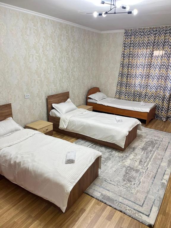 a room with three beds and a rug at DARAI guest house Hostel Turkistan in Türkistan