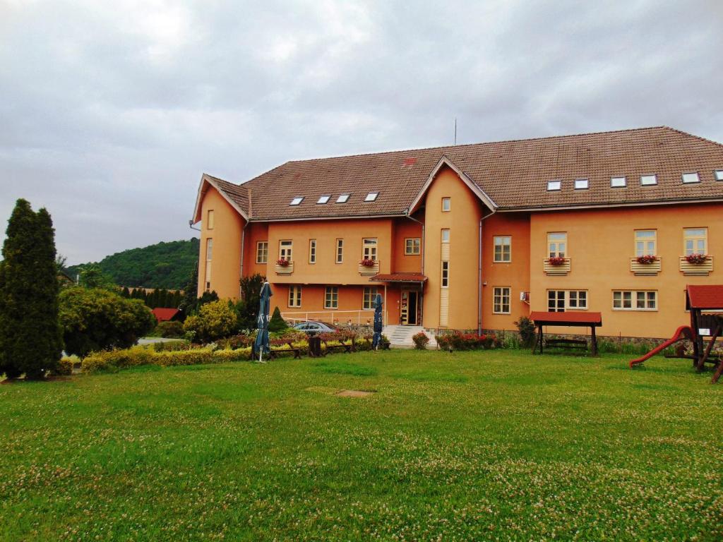 a large building with a grass field in front of it at Pensiunea Praid - Parajd Panzió in Praid