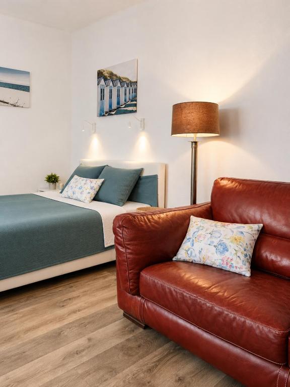 a bedroom with a bed and a leather couch at Esther's Studio Keszthely in Keszthely
