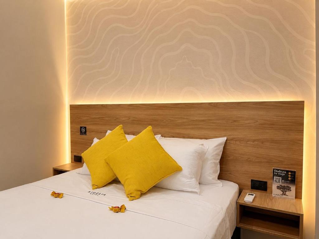 a bedroom with a bed with two yellow pillows at Kigelia Hotel in Tumbes