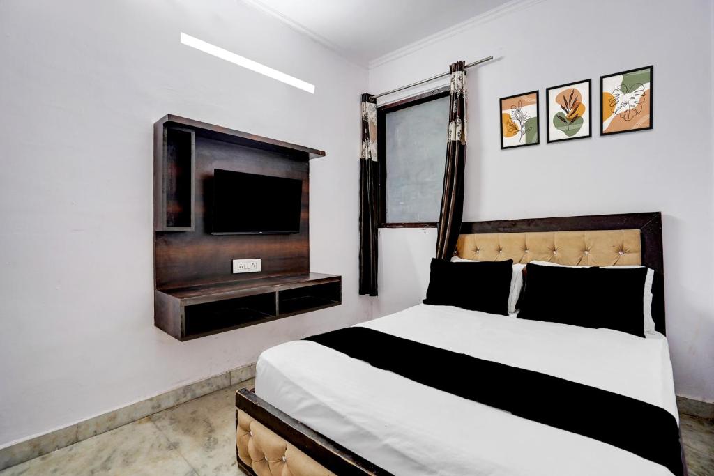 a bedroom with a bed and a flat screen tv at Hotel O A-1 Guest House in New Delhi