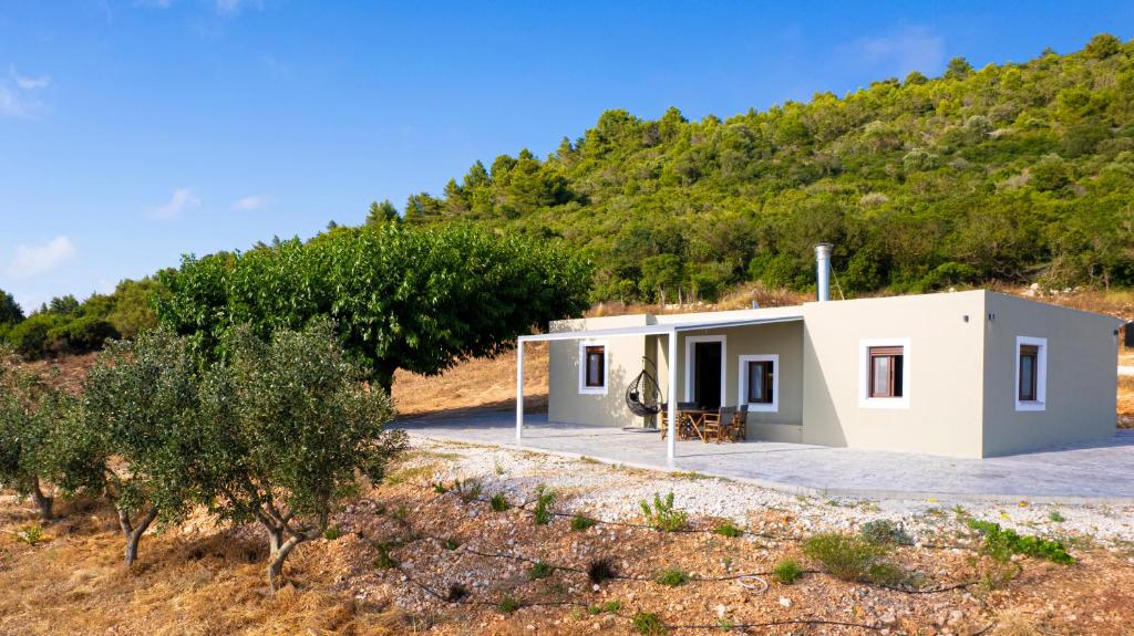 a small white building with a hill in the background at Mulberry Tree House in Póndi