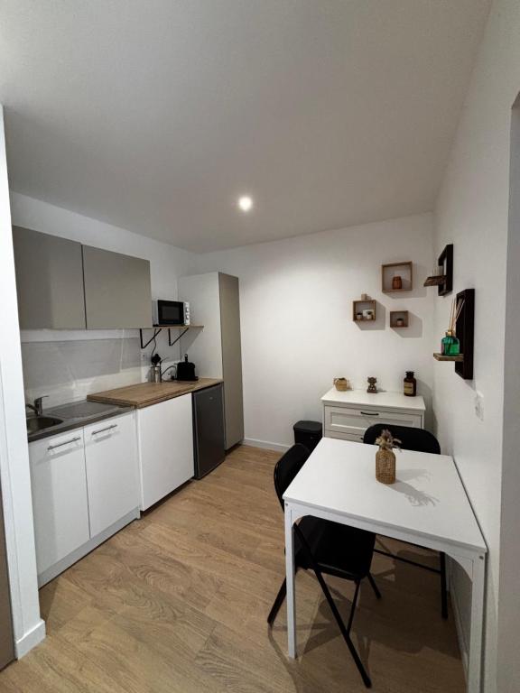 a kitchen with white cabinets and a table and a stove at La Cigalière 2 charmant T2 avec terrasse dans villa in Solliès-Ville