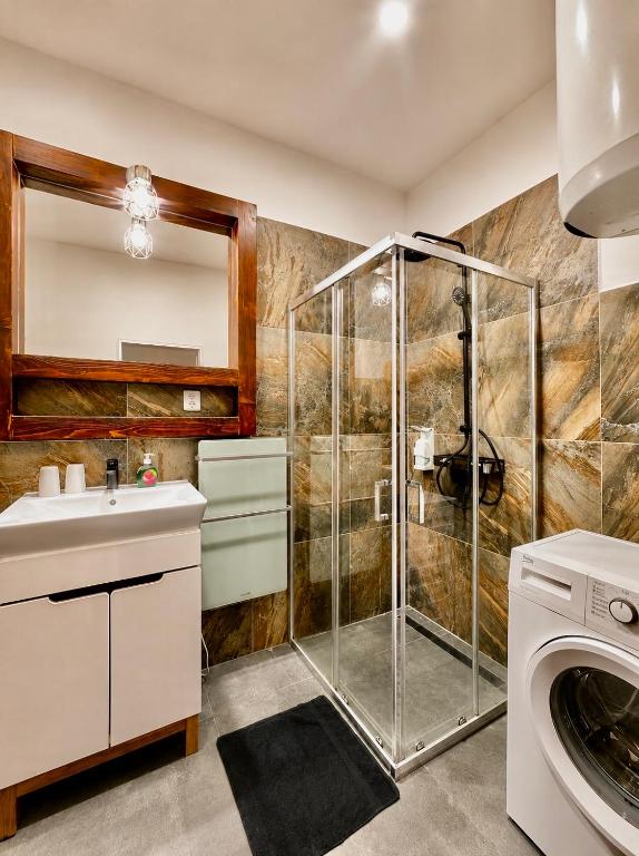 a bathroom with a shower and a sink and a washing machine at Kael Apartment in Teplice
