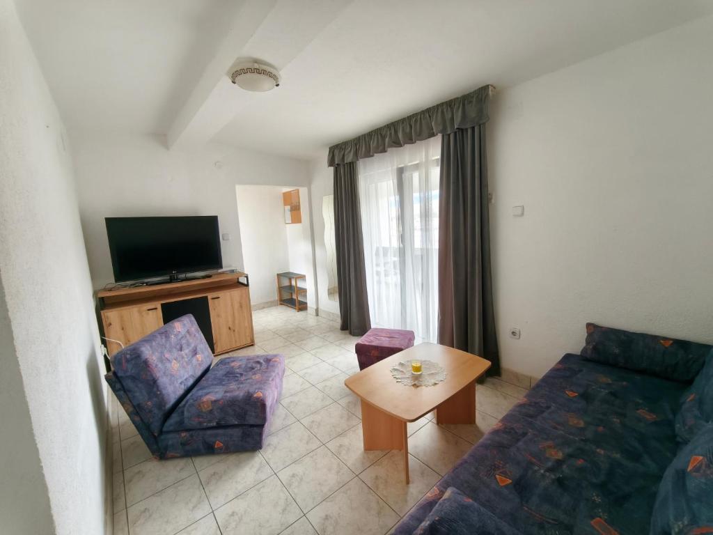 a living room with a couch and a tv at Apartments Šešo A in Pag