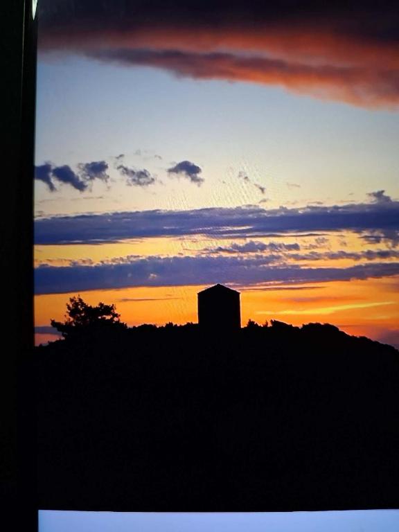 a silhouette of a building in front of a sunset at Iliovasilema in Vathý