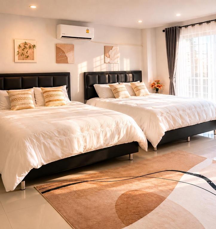 two beds in a large bedroom with a rug at Nasrina's House Hat Yai ใกล้เซ็นทรัลหาดใหญ่ in Sathani Khlong Rian