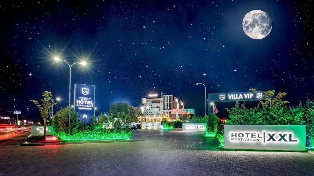a city at night with the moon in the sky at Hotel XXL in Ferizaj