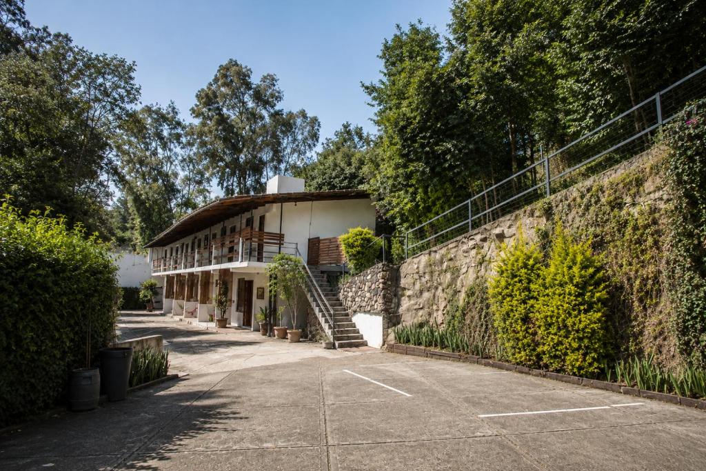 a building next to a wall with a parking lot at Meson de Valle Hotel in Valle de Bravo