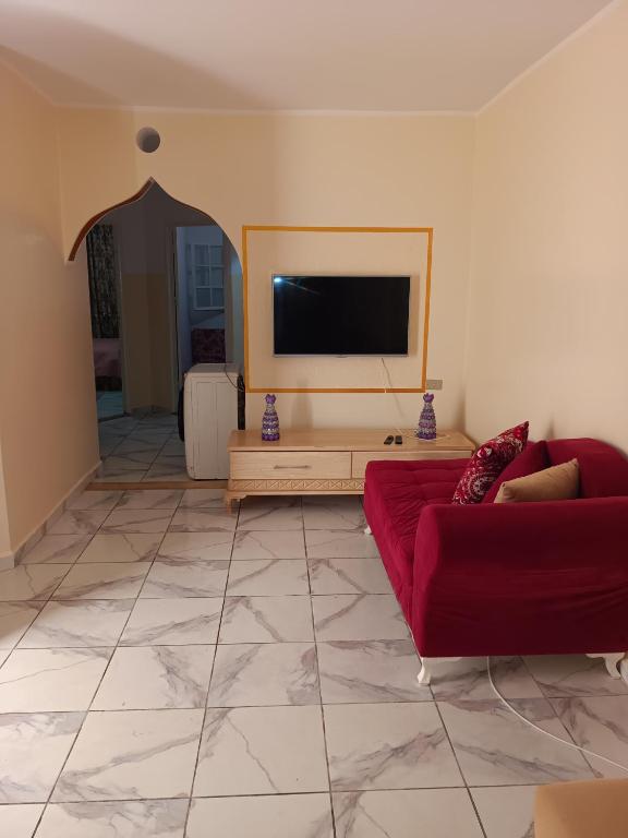 a living room with a red couch and a flat screen tv at Dar Khuwayra in El Haouaria