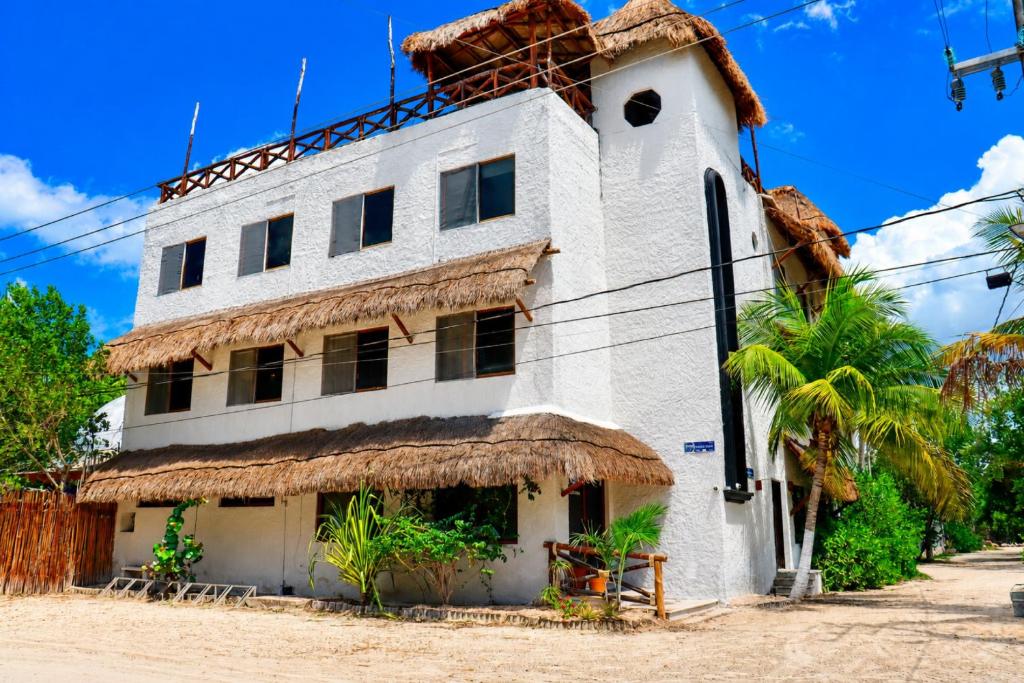 an old white building with a thatched roof at Paseo Kuka by ÓOL Hotels in Holbox Island