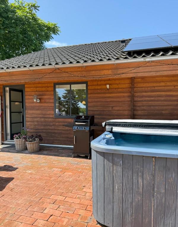 a large hot tub sitting outside of a house at Fredfyldt skovbolig med udespa in Rødding