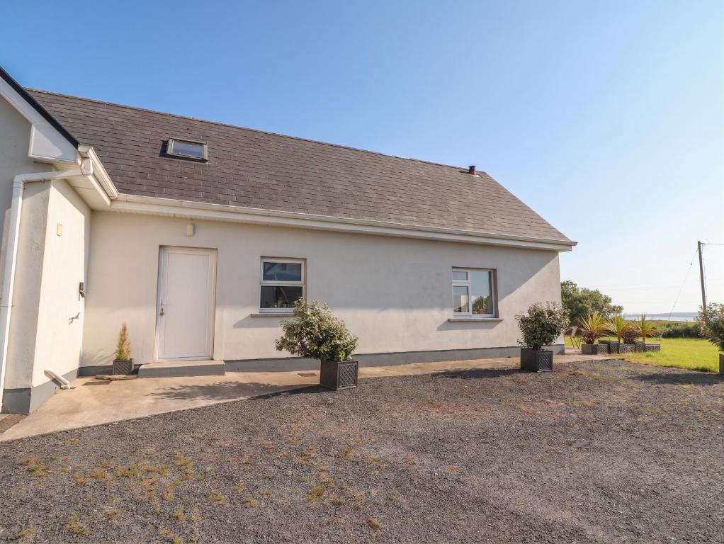 a white house with two potted plants in front of it at The Boathouse in Kilkee