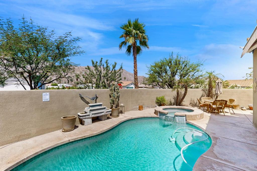 a swimming pool in a backyard with a table and chairs at Lovely La Quinta - 66318 in La Quinta