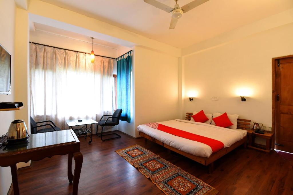 a bedroom with a bed and a desk and a window at Hotel O by OYO Manali Meadows Home Stay in Manāli
