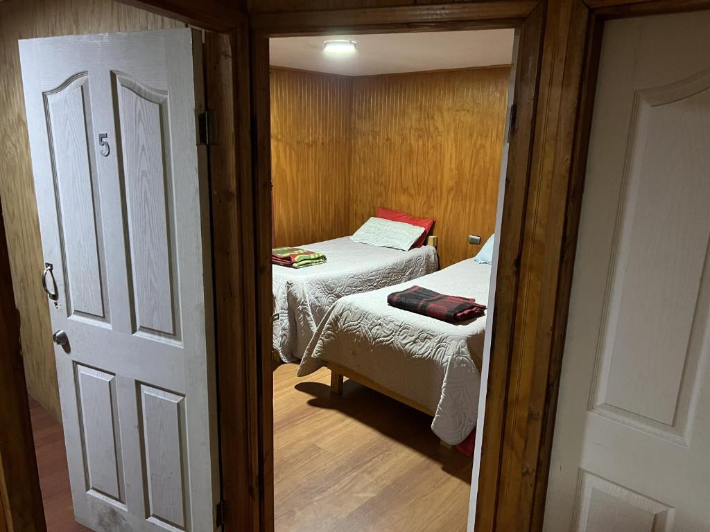 a small room with two beds and a doorway at Hospedaje Ilabaca in Angol