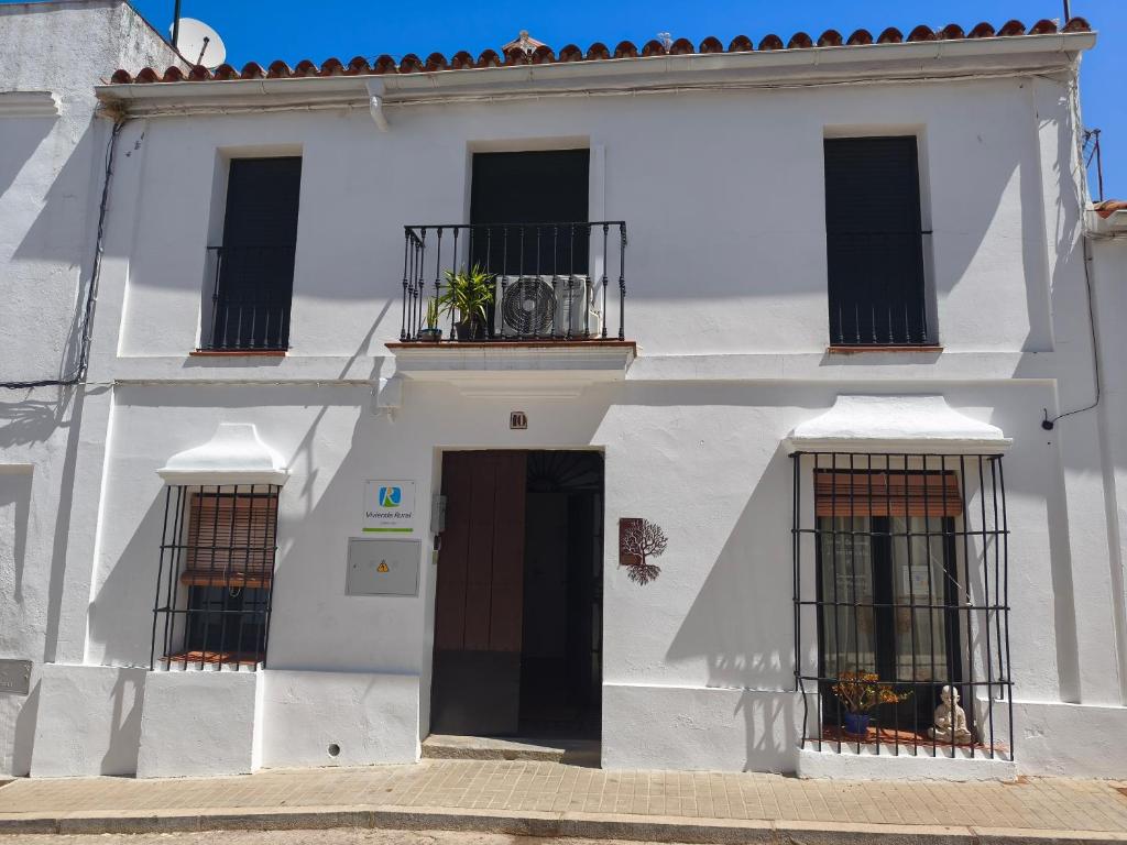 a white building with three windows and a door at El Refugio in Aracena
