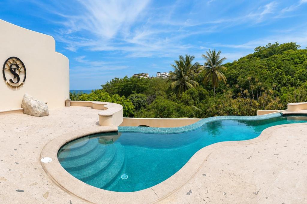 a swimming pool on top of a resort with trees at The Sanctuary Boutique Hotel in Tangolunda