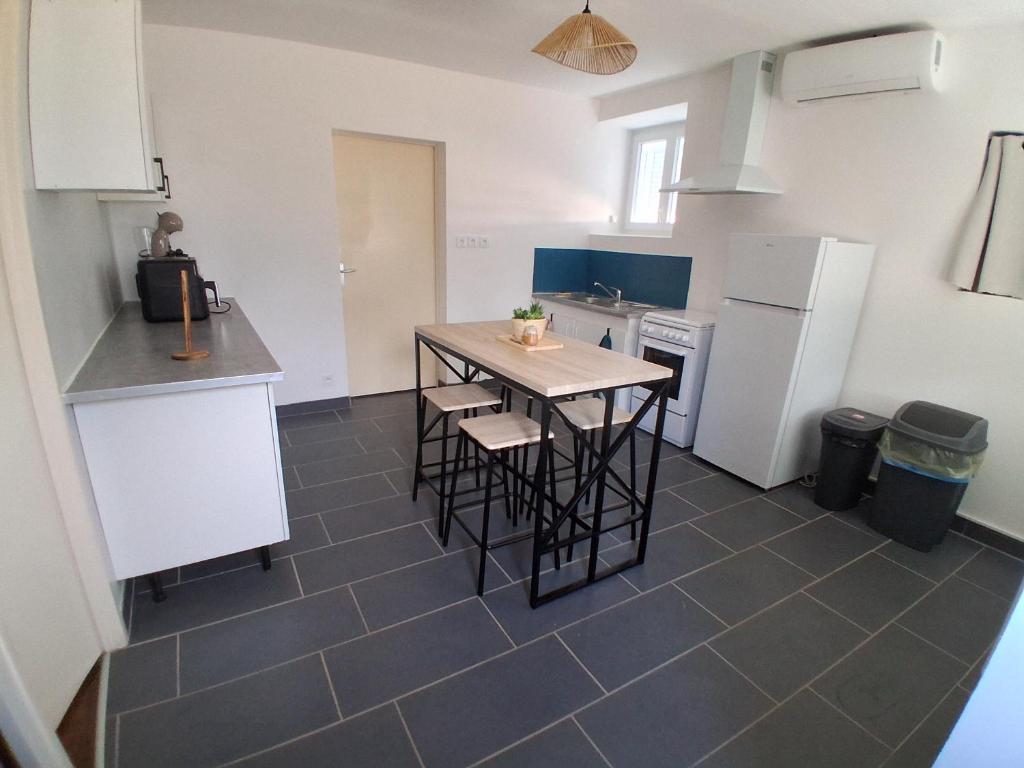 a kitchen with a table and some chairs and a refrigerator at Agréable Maison in Le Magny