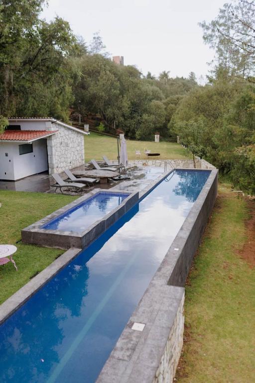 a swimming pool with blue water in a yard at Finca en el Bosque Huasca de Ocampo con Alberca in Huasca de Ocampo