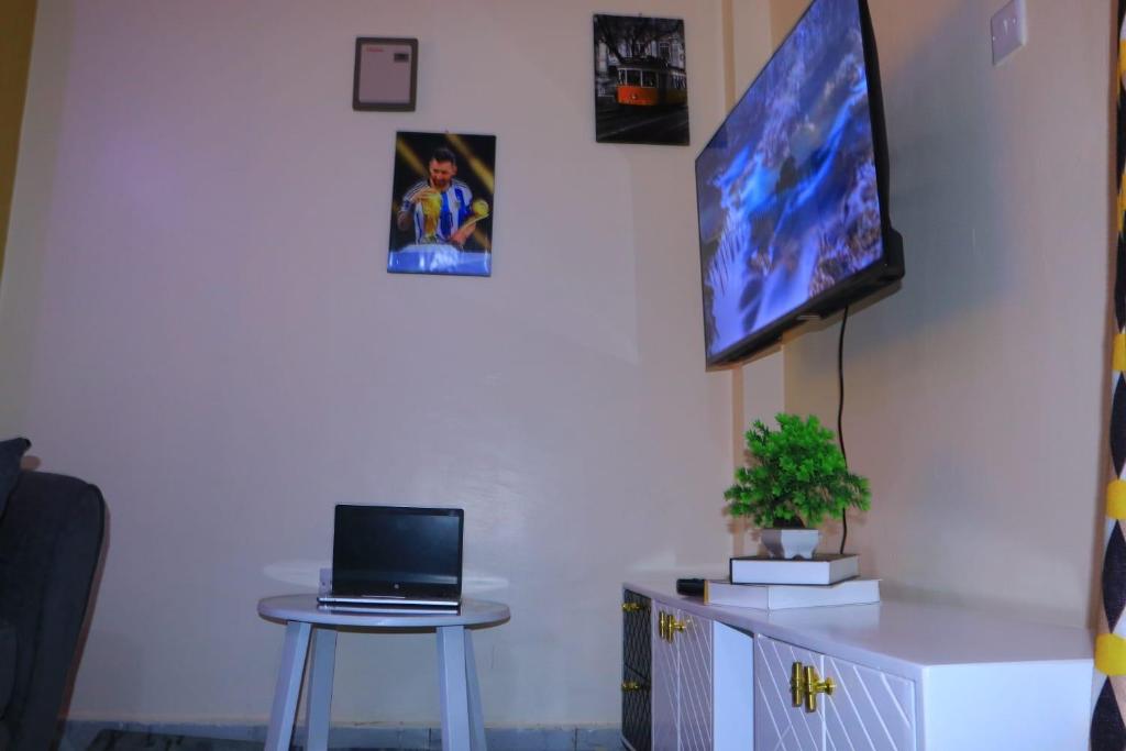 a room with a table and a tv on a wall at Cedar Suites in Juja