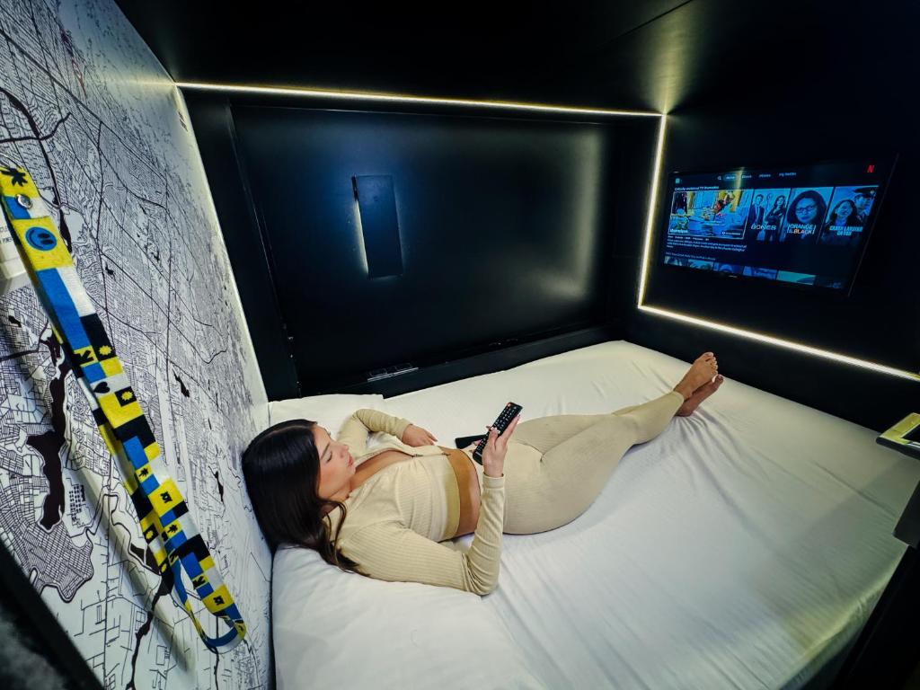a woman laying on a bed looking at a cell phone at Hostal Joy Calle 85 in Bogotá