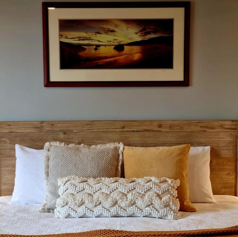 a bed with a wooden head board with a picture on the wall at Brushwood Studio - Eco Hideaway - Denmark WA in Denmark
