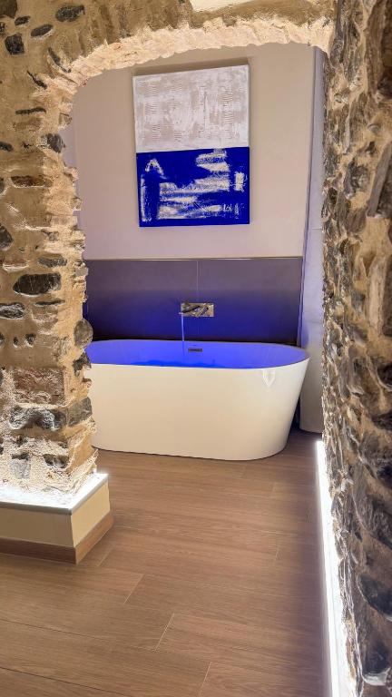 a bath tub in a bathroom with a stone wall at Nervia Rooms by Talking Stones in Dolceacqua