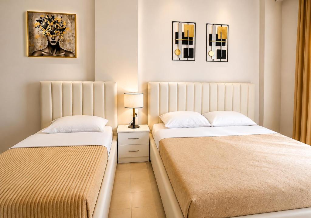 a bedroom with two beds and a lamp on a table at Villa Arli&Eris in Vlorë