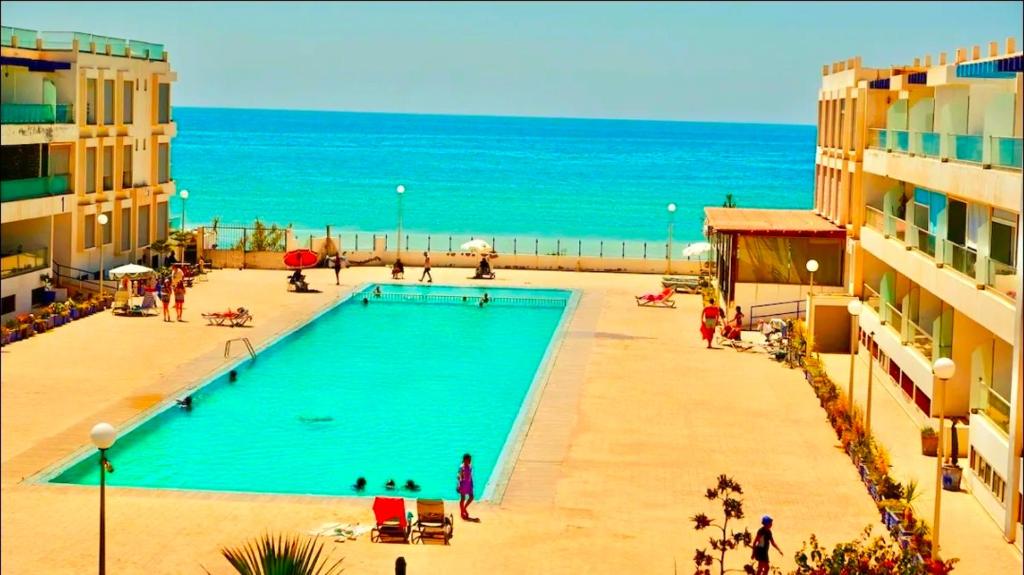 a swimming pool on the beach next to some buildings at Cozy apartment adana in Aourir
