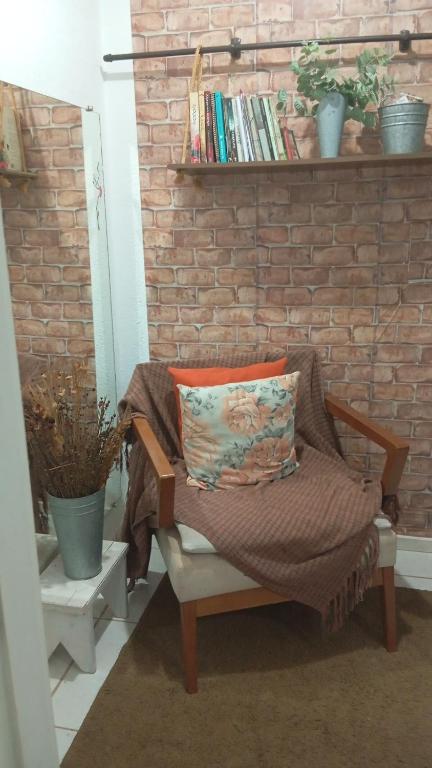 a chair with a pillow sitting in front of a brick wall at Small family apartment in Sao Sebastiao