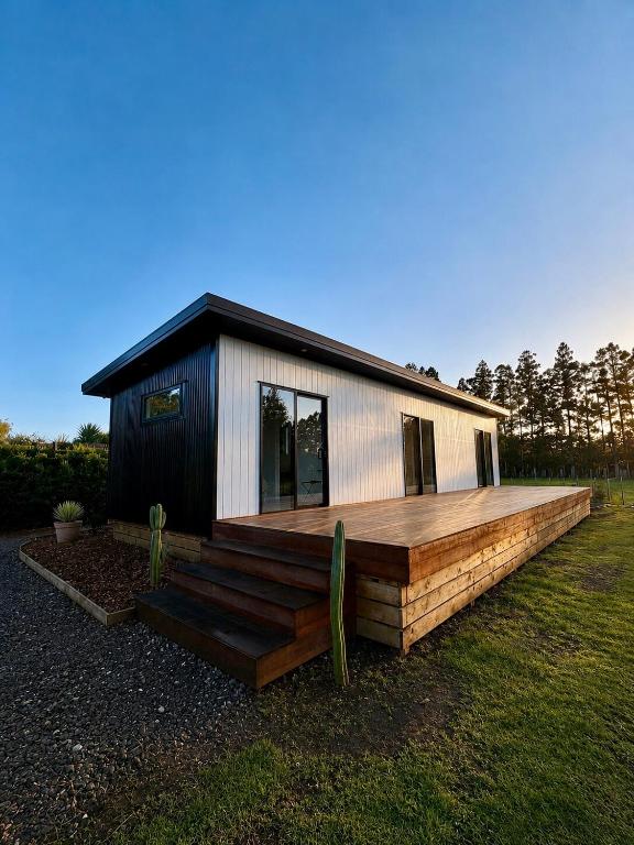 a small house with a large wooden deck at The palms farmhouse in Puketona