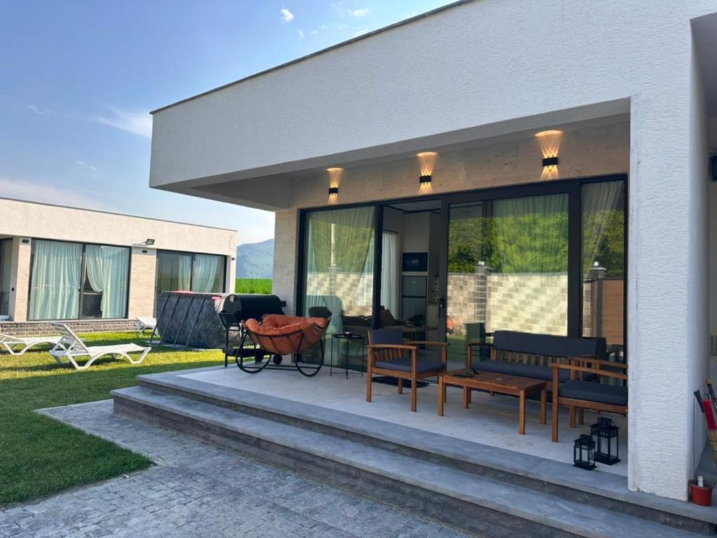 a house with a patio with benches and tables at Modern Mountain Villa with Pool near Tbilisi in Bulach'auri
