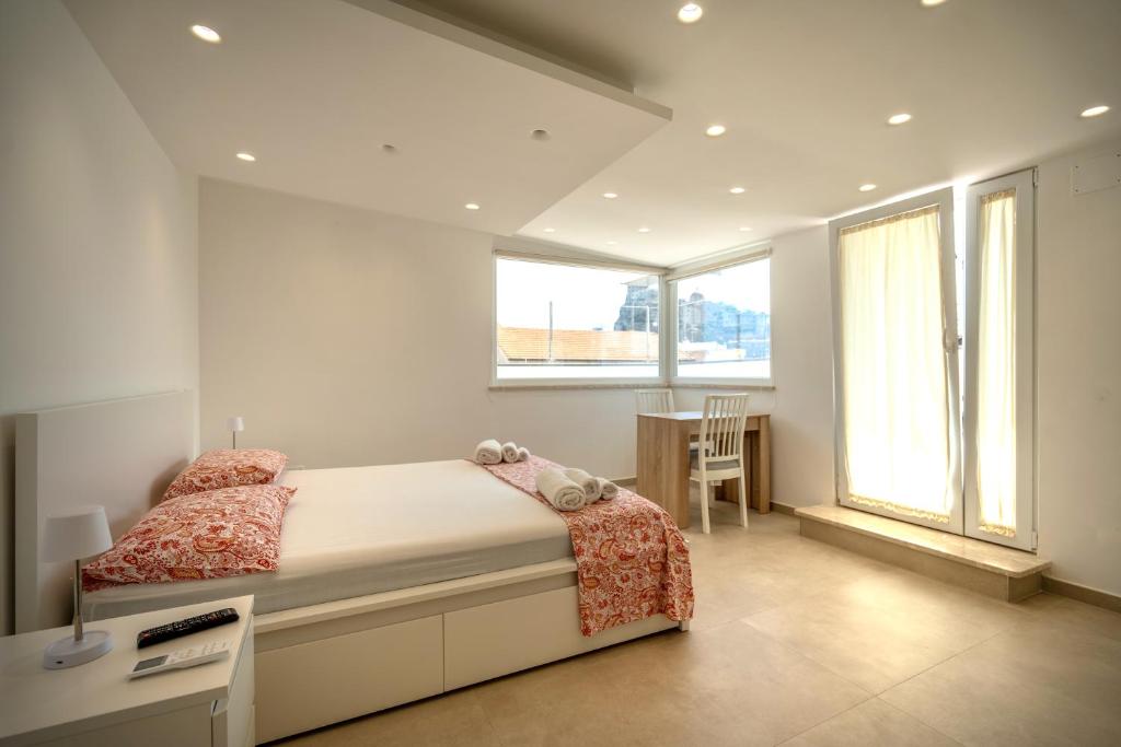 a bedroom with a bed and a desk and windows at Aragonese Apartments in Casa Chiaiozza