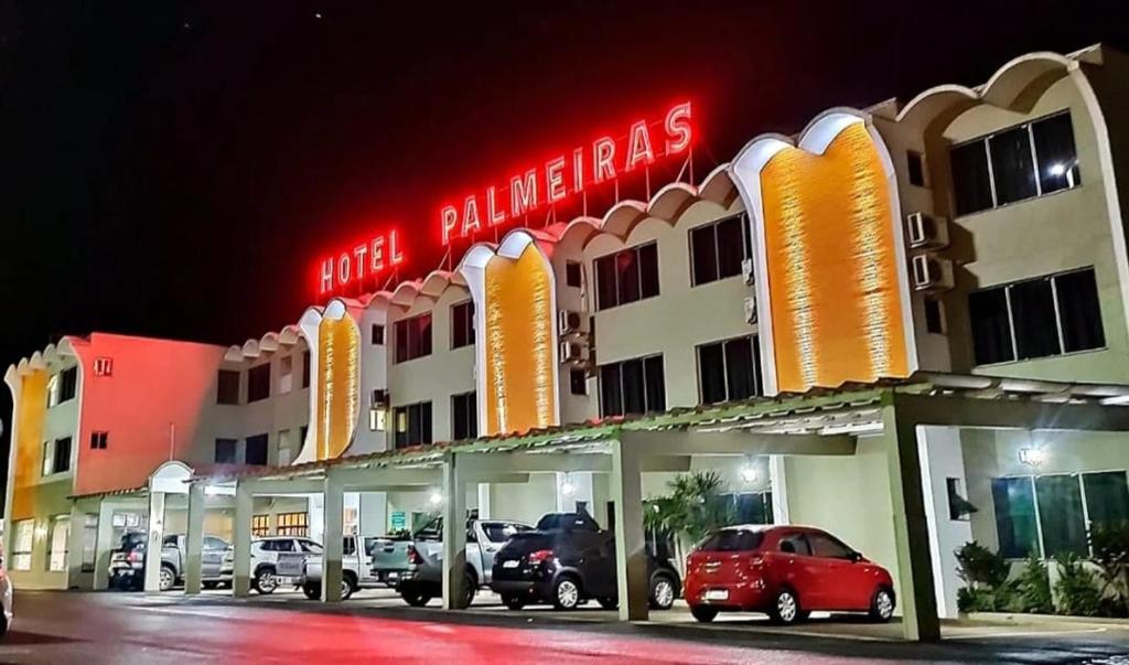 a hotel building with cars parked in front of it at Hotel Palmeiras in Laranjeiras do Sul