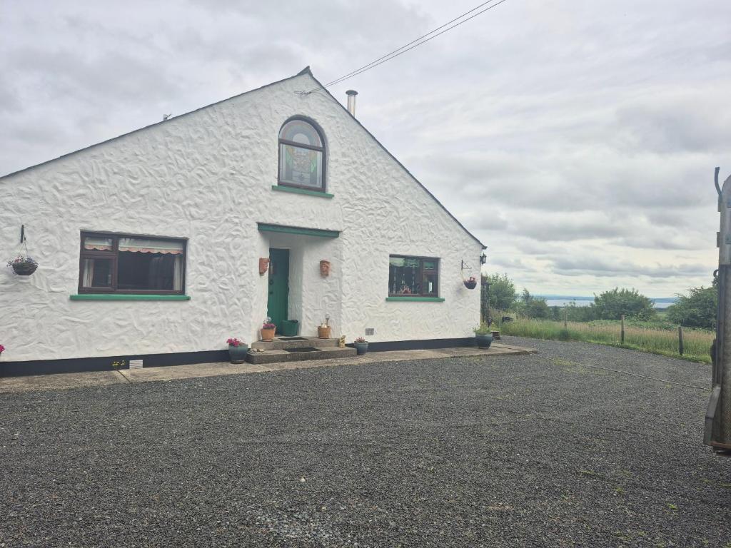 a white cottage with a green door and windows at Rainbow Cottage Glenmore in Dundalk