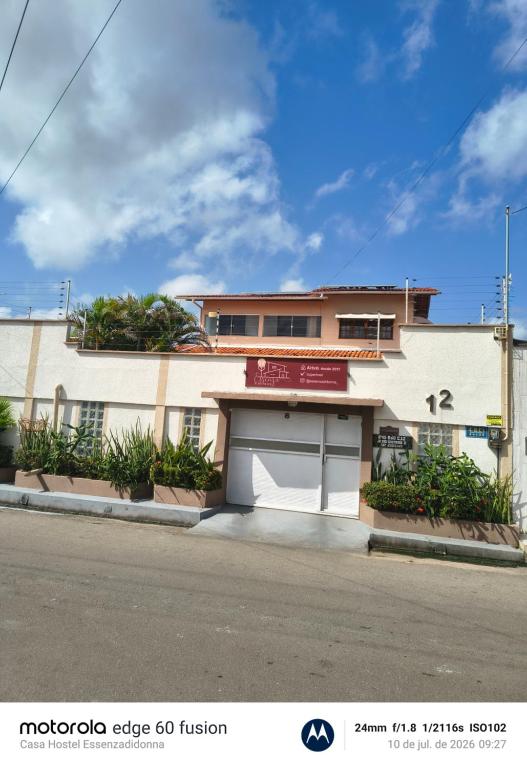 a white building with a garage on a street at Casa Hostel Essenza di Donna in São Luís