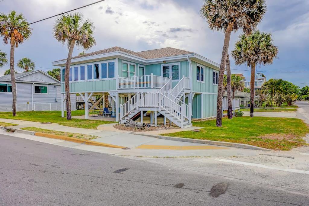 a blue house with palm trees in front of it at Hazel Q in Edisto Island