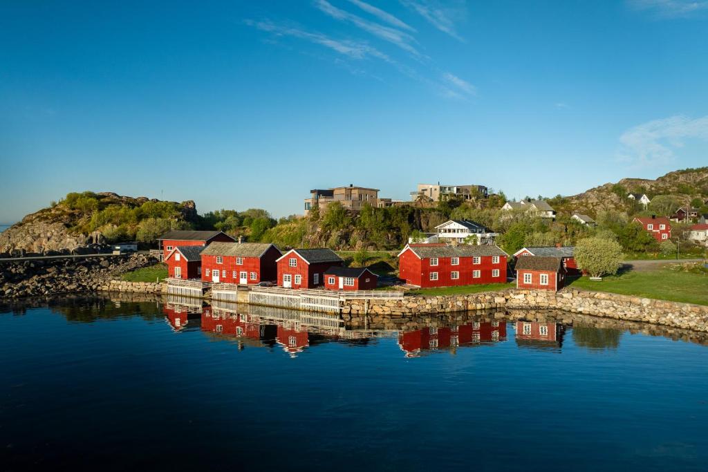 a group of red houses next to a body of water at Astra Village - Waterfront Rorbu Cabins in Lofoten in Kabelvåg