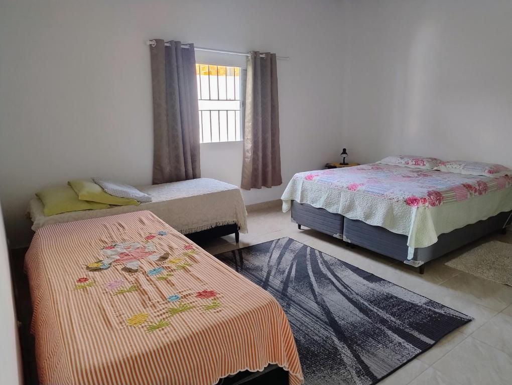 a bedroom with two beds and a window at Microcasa espaçosa e acolhedora in Caraguatatuba