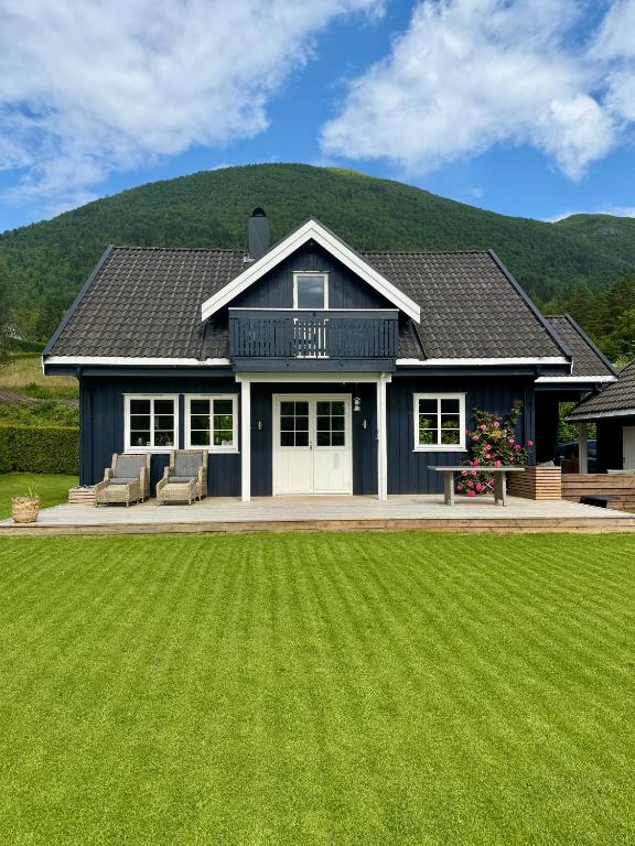 a black house with a large lawn in front of it at Scenic Private House Surrounded by Nature in Sæbø