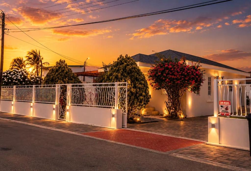 a white house with a white fence and trees at Villa Fina Aruba in Palm-Eagle Beach