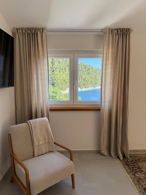 a chair sitting in front of a window at Villa Ljeto in Pupnatska Luka
